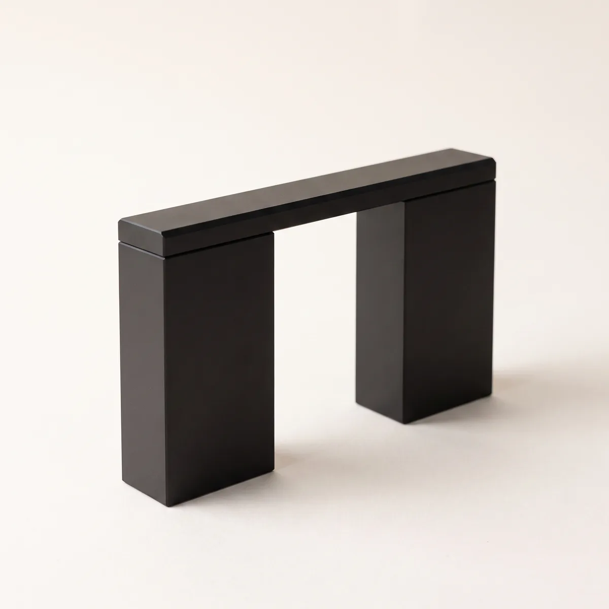 Two matte-black blocks joined across the top by a single machined beam — a bridge between systems.